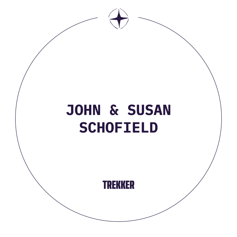 This is a circular logo with the text "JOHN & SUSAN SCHOFIELD" in the center, above the word "TREKKER". A small compass rose graphic is centered at the top of the circle. The overall design is minimalist and modern, suggesting a brand or personal identity related to travel or adventure.